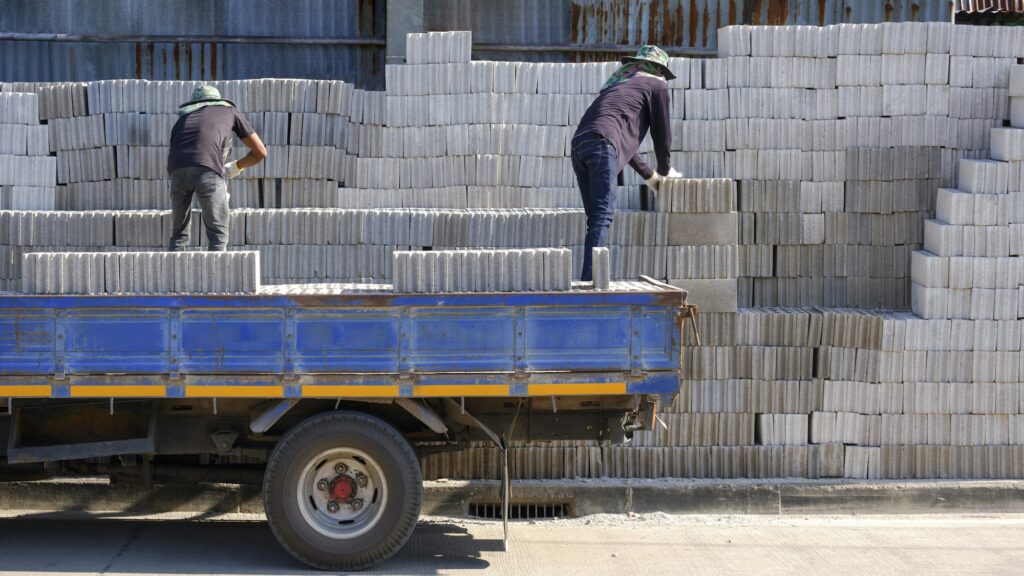 Rear view of 2 Asian workers are loading concrete blocks into the truck for delivery to customers
